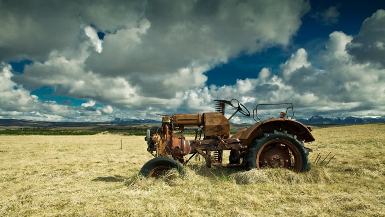 old_rusty_tractor_in_hay_field.jpg