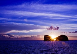 sunset through an ocean rock island