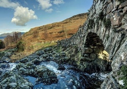 stone bridge over rocky mountain stream hdr