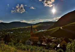 bright sun on a church in a river valley town