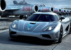 koenigsegg at an airport of old mig planes