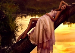 Sensual girl lying on a tree trunk