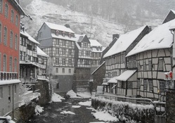 river through an alpine town in snow shower
