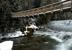 lovely pedestrian bridge over waterfall in winter