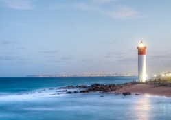 marvelous lit lighthouse with city in the background