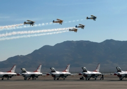 a flight of biplanes over f16 thunderbirds